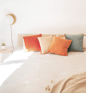 five square decorative pillows on a neutral bedding set 