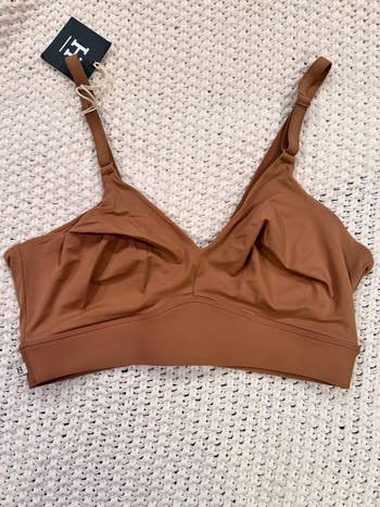 Woman's seamless bralette with thin adjustable straps on a textured background
