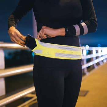 model slipping a phone into their yellow flipbelt attached at the waist