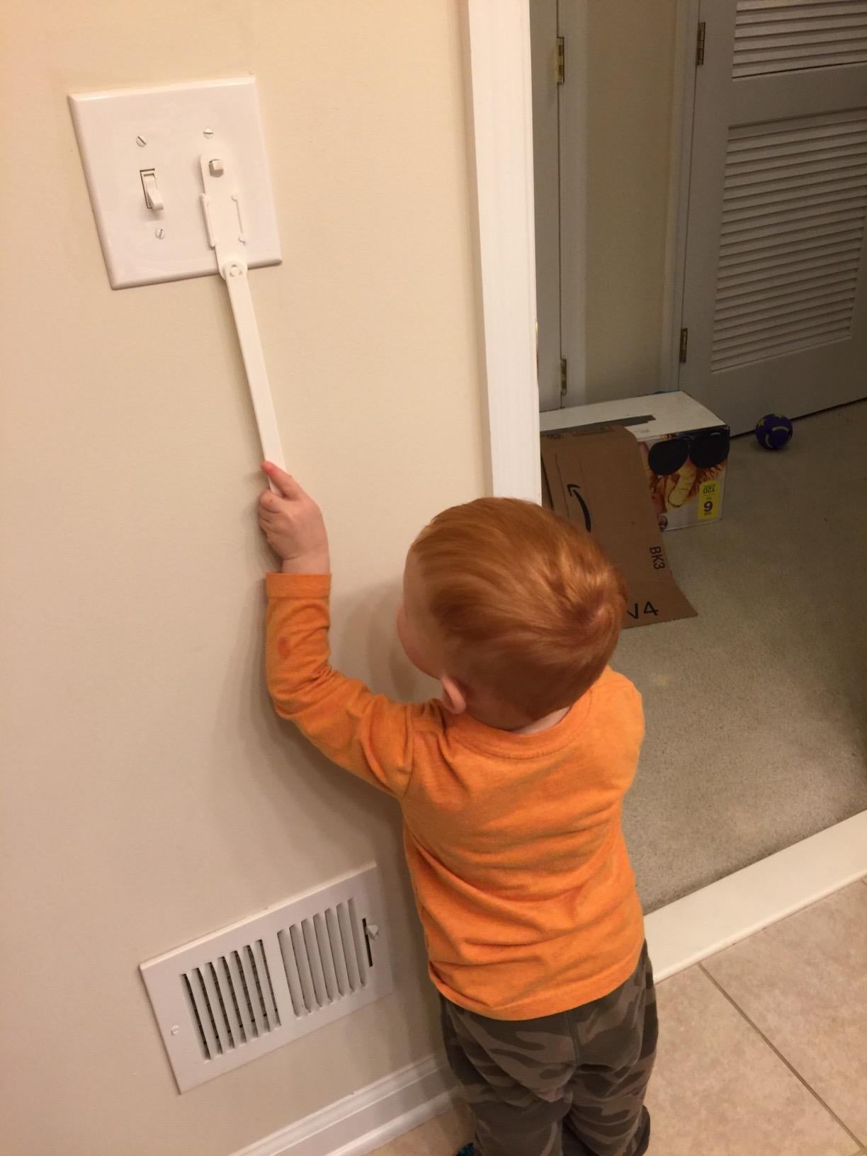 a young child pulling the extender to flip a light switc