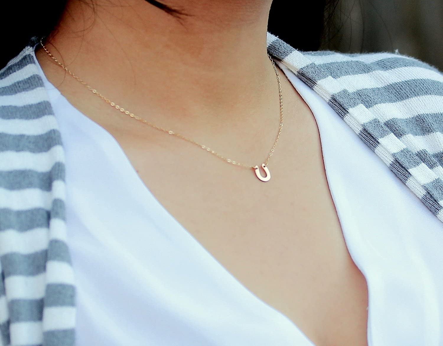 a delicate gold necklace with a horse shoe charm
