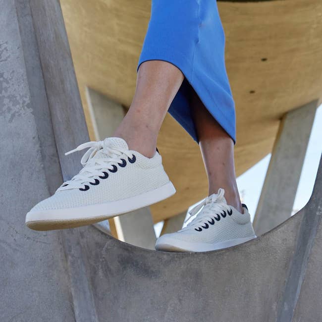 Person wearing stylish sneakers and a skirt stands connected  a factual  structure. Featured successful  an nonfiction  astir  trendy footwear shopping