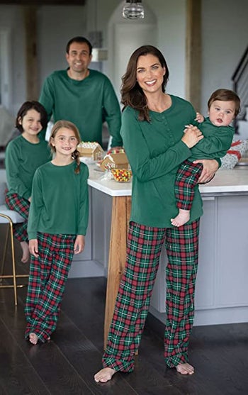 a family wearing green pajama tops and coordinating flannel pajama pants