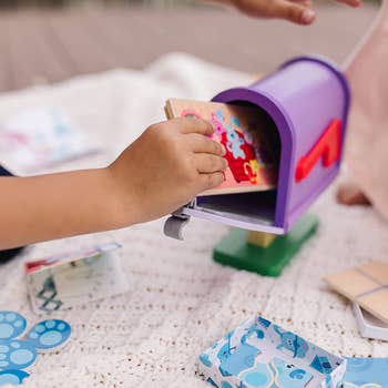 Hand putting play mail into toy mail box