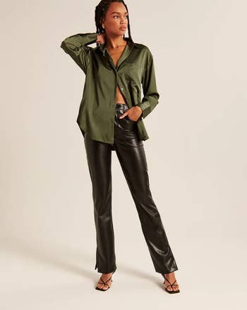 a model wearing black vegan leather pants with a green button down