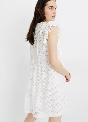 a model in a white eyelet dress with ruffled sleeves