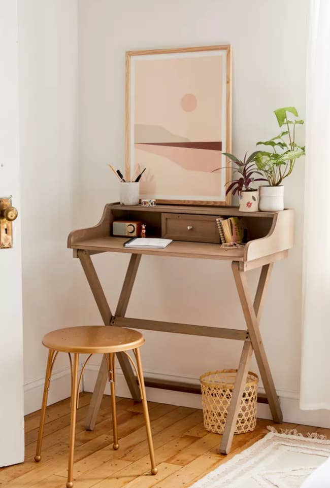 wood folding desk with small drawer in the center tucked away in small room corner