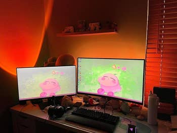 a reviewer's multi monitor setup with led strips creating a red orange glow behind them