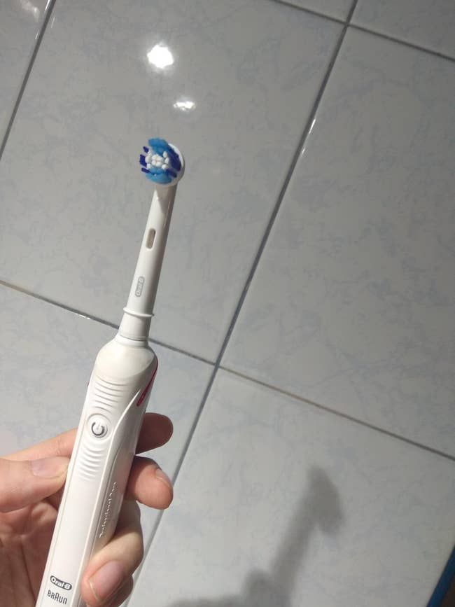 A reviewer holding the white toothbrush