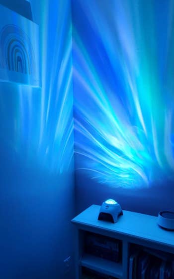 A projector casts blue dynamic wave patterns on a wall