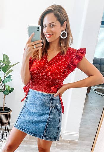 reviewer wearing the red polka dotted shirt with a denim skirt