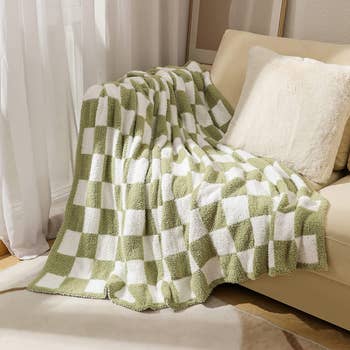 A green and white checkered blanket draped on a couch 