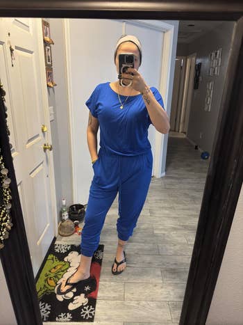 Person successful  a casual bluish  jumpsuit and slippers, taking a reflector  selfie astatine  home