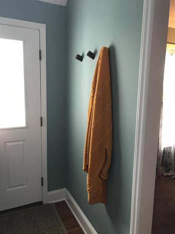 reviewer using the hooks in the entryway to hold a sweater