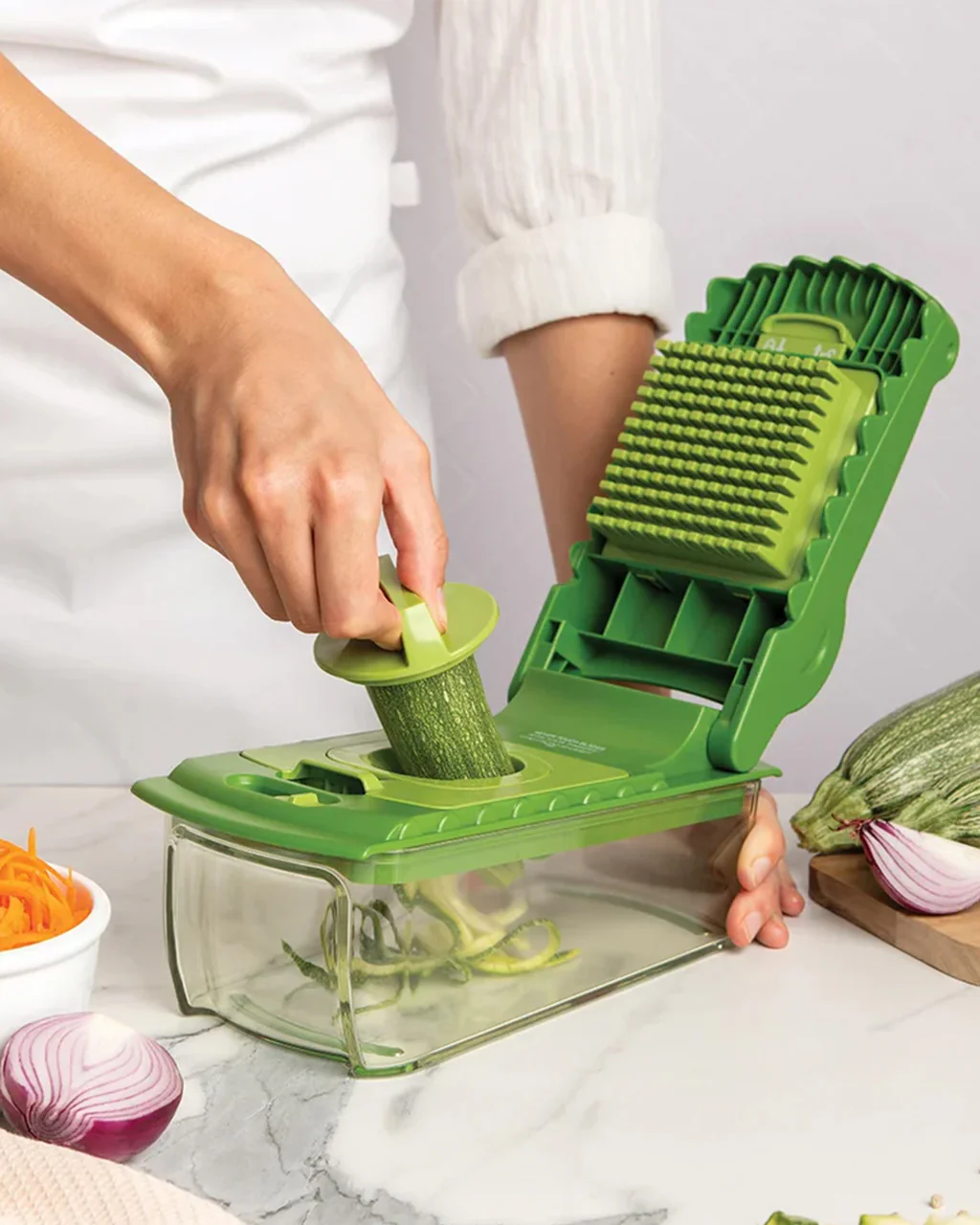 Person using a vegetable slicer to cut a zucchini on a kitchen counter