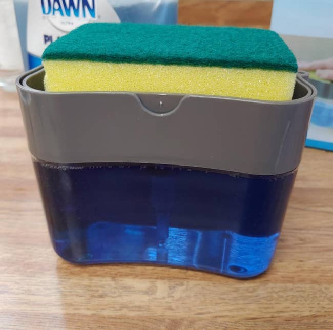 reviewer's soap dispenser where the top of the dispenser also acts as a caddy for the dish sponge