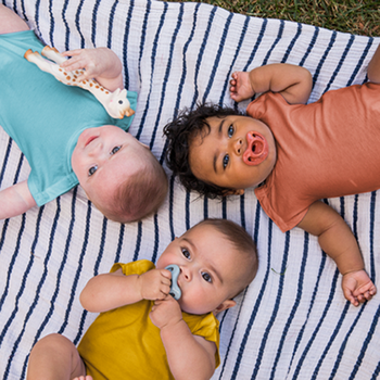 three babies in blue, orange, and yellow onesies