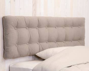 Tan tufted cushion attached to wooden wall above bed