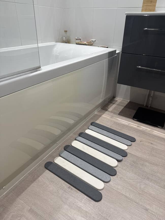 Modern bath  with a bathtub and a striped non-slip rug connected  the floor, cleanable   for stylish and harmless  decor