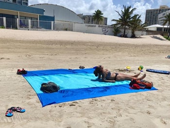 another reviewer laying on the blanket at the beach