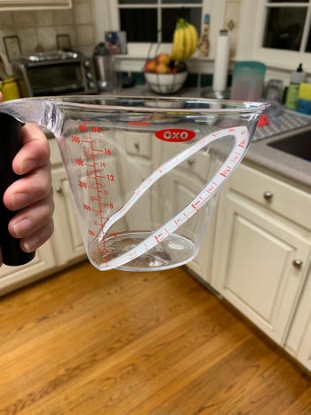 a reviewer holding the cup and showing the side view with the angled measurements inside