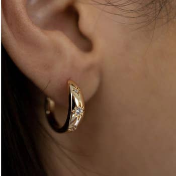 model wearing gold and star hoop earring