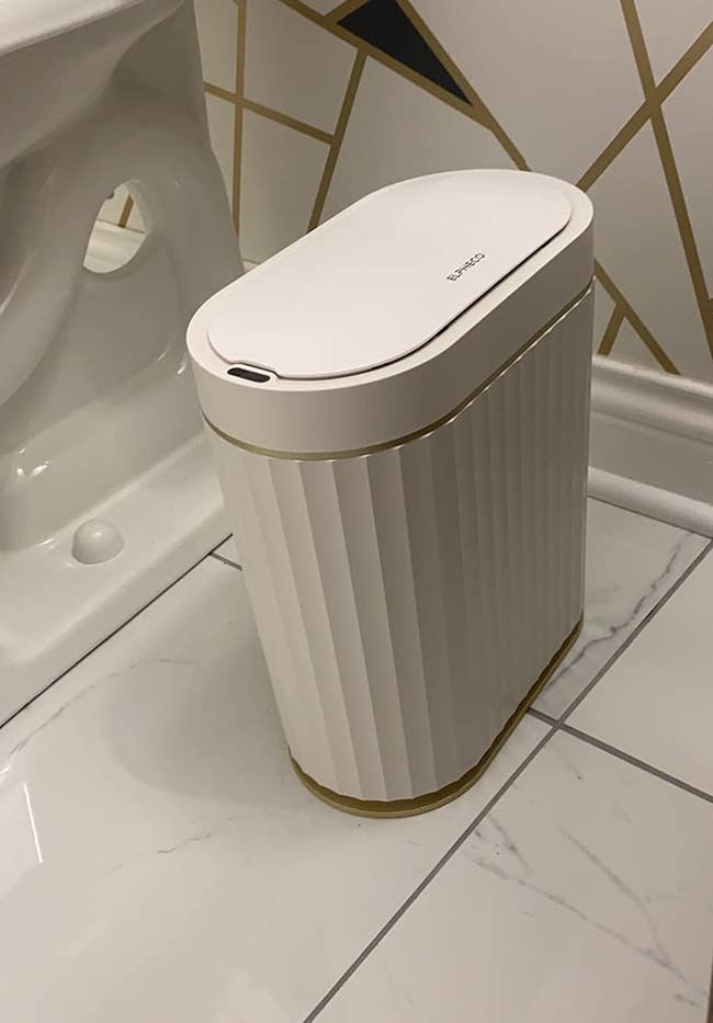 reviewer's narrow white trash can next to toilet
