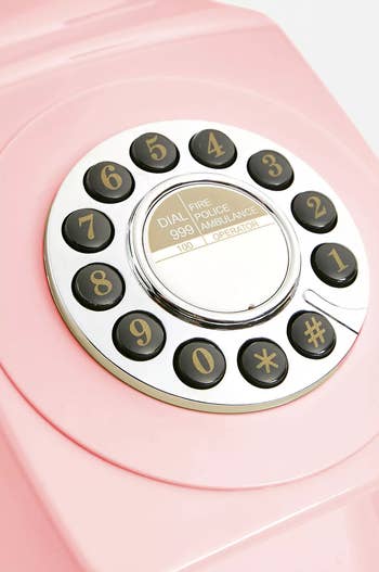 Close-up of a vintage rotary telephone dial with numbers and emergency instructions, highlighting retro style for a shopping article