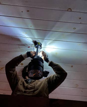Reviewer wearing the gloves to fix a light fixture in the dark 