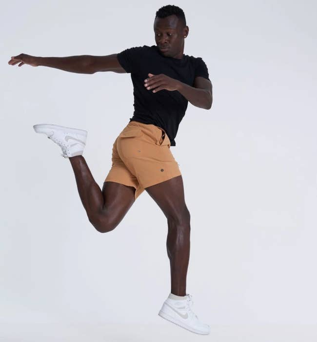 Model is wearing the yellow shorts, a black top, and white sneakers