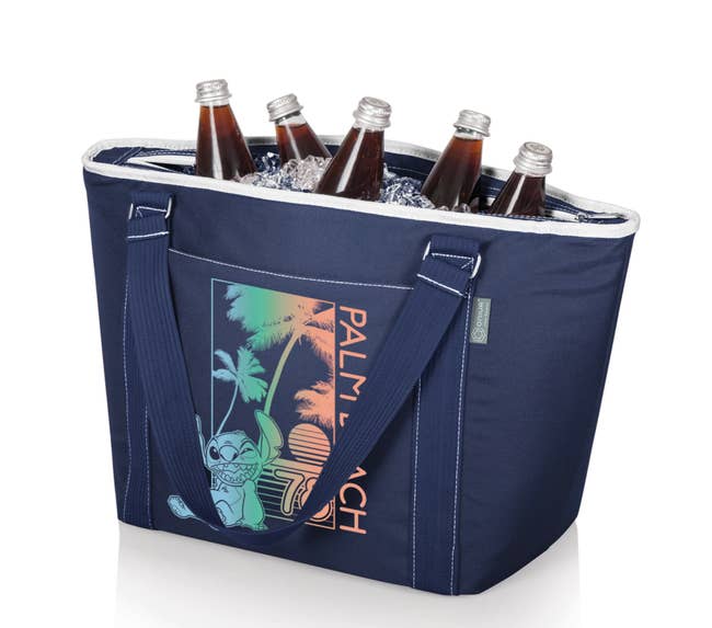the navy cooler tote filled with ice and bottles of soda featuring a print of stitch and text that reads palm beach 78