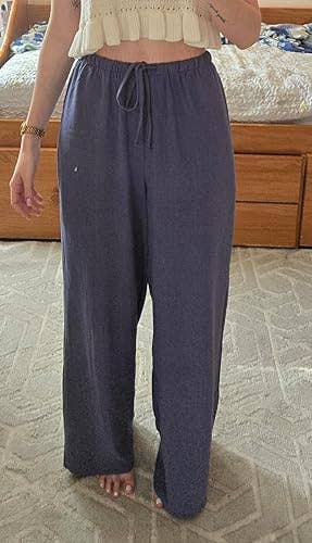 Person wearing loose-fitting pants with a drawstring waist and a cropped knit top, standing indoors, showcasing a comfortable fashion look