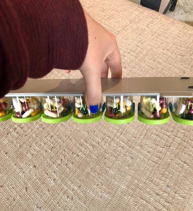 reviewer holding green and blue weekly pill organizer filled with different vitamins