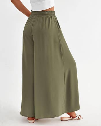 Wide-legged green pants with pleats, paired with white sandals