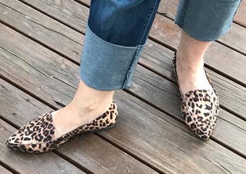 a reviewer wearing jeans and a pair of pointed-toe loafers with an animal print 