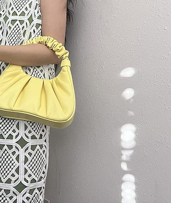 reviewer wearing the yellow ruched bag around their arm
