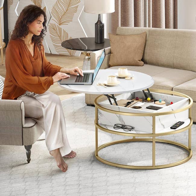 Model using a laptop at the round coffee table with gold metal base