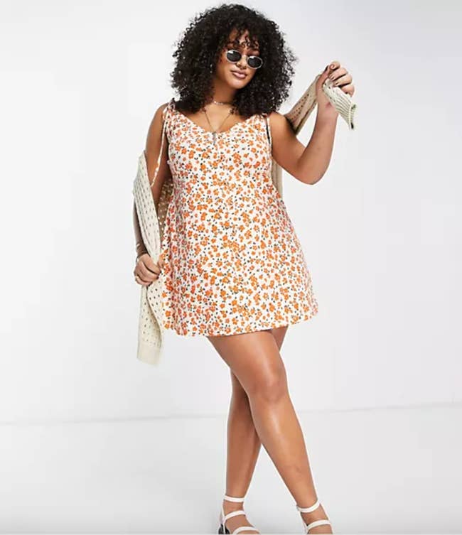 model in a white tie-string sleeveless mini dress with orange floral pattern 
