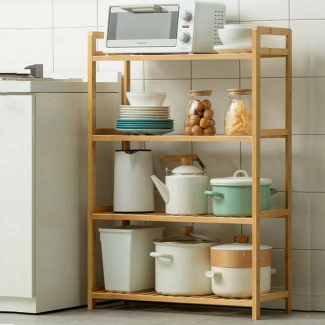 Kitchen shelf with a toaster oven, plates, bowls, jars, and various cookware neatly arranged