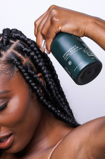 a model spraying the curl elixir on their roots