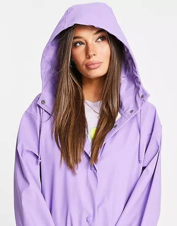 model wearing a lavender raincoat with hood up