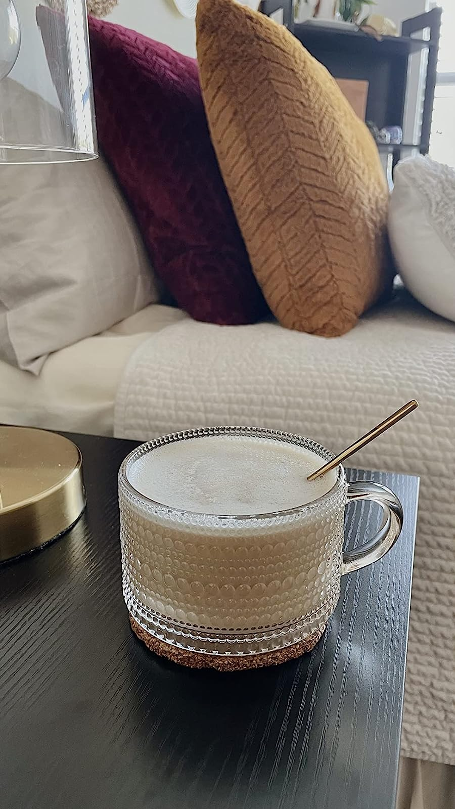 A glass cup with subtle cut out line and dot patterns holding coffee 