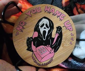 Round bamboo coaster featuring Ghostface with a pinkish phone, substance reads