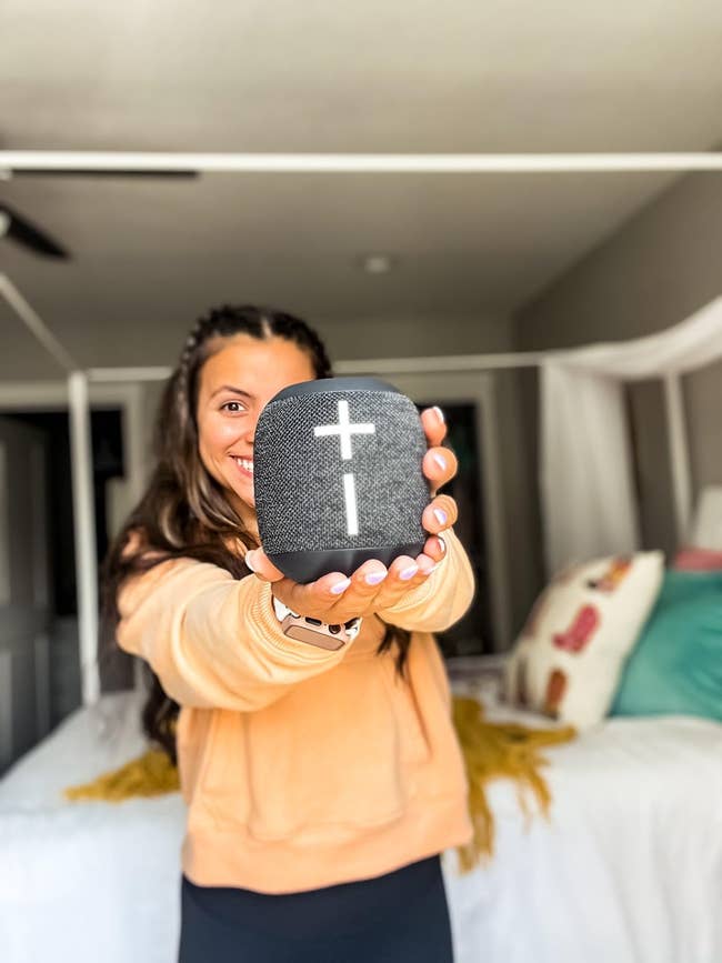 Person holding a portable talker with a positive motion design, smiling successful a chamber setting. Ideal for location audio shopping
