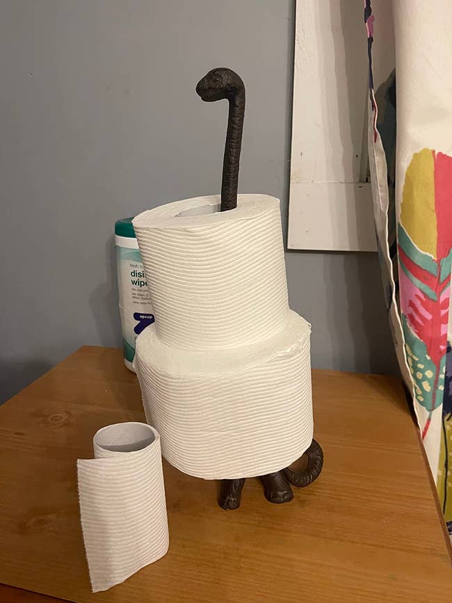 Stack of toilet insubstantial  rolls connected  a holder with an carnal  paw base, adjacent  to a disinfectant wipes container