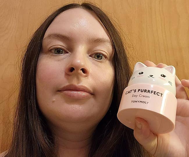 fresh-faced reviewer holding up the cat-shaped cream container