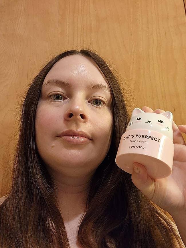 fresh-faced reviewer holding up the cat-shaped cream container