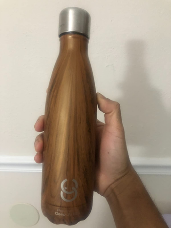 a reviewer holding a wood-tone water bottle 