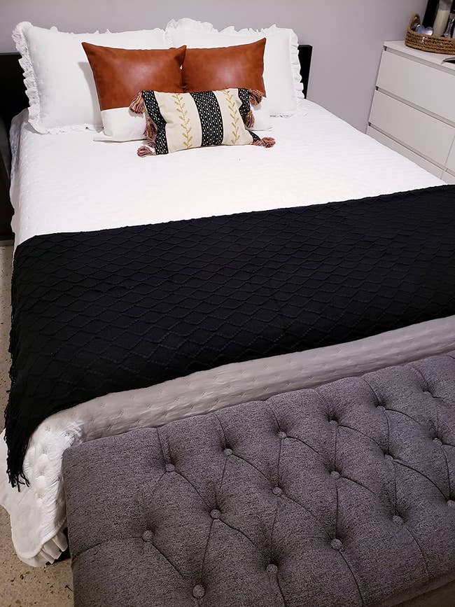 reviewer image of the two tan faux-leather pillows on a bed