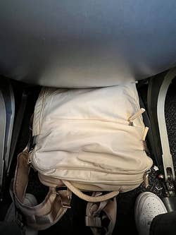 same reviewer's beige backpack under the airplane seat